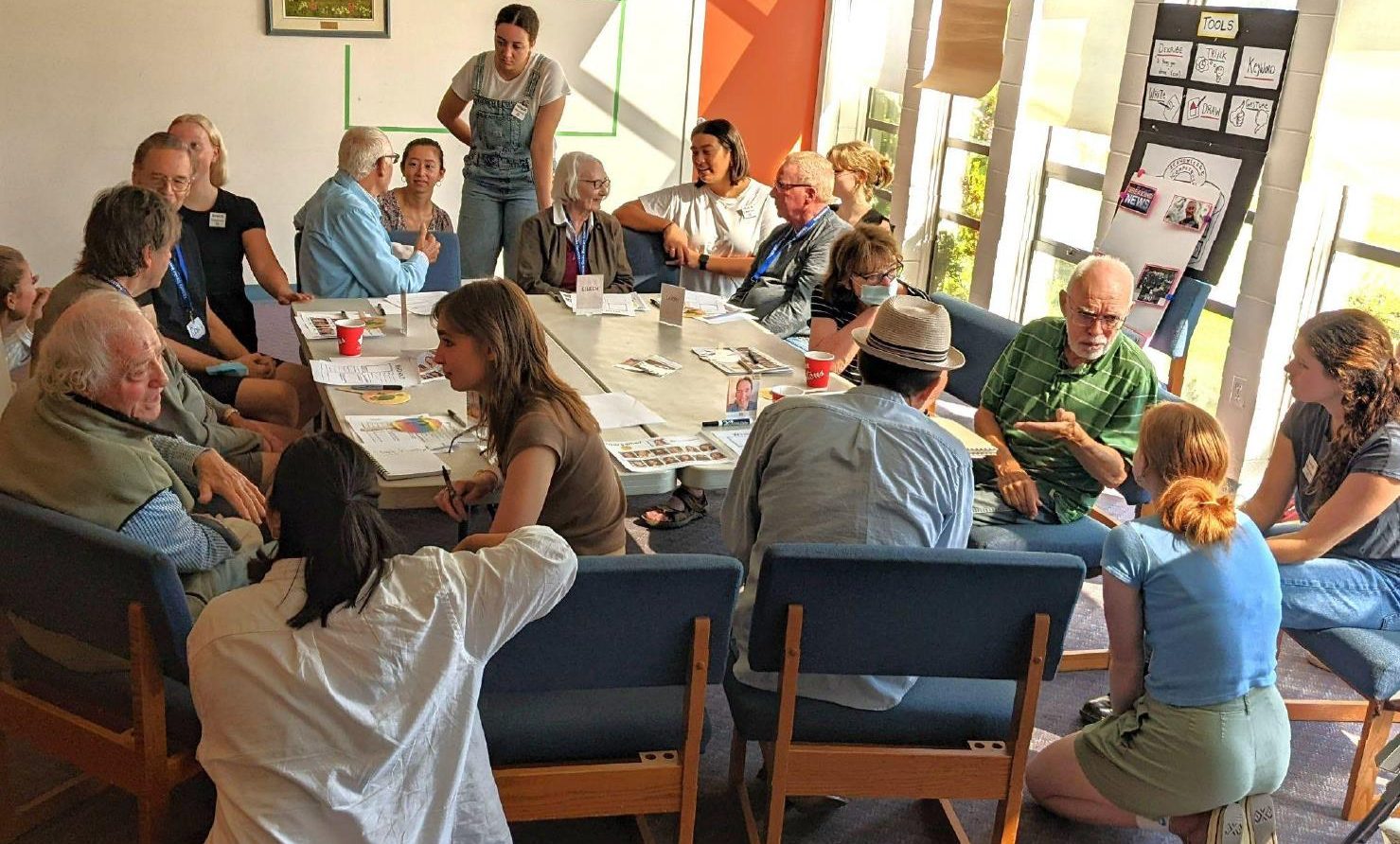 Young women and men at a table with older people talking closely
