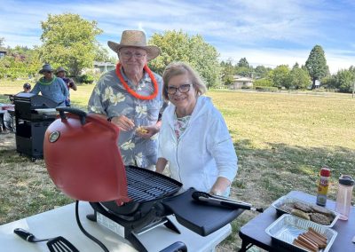 Two VSRA members, a man and woman, standing at the grill cooking hot dogs and hamburgers