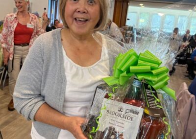 Woman smiling broadly because she won a big food basket from the Victoria Stroke Recover Association -- at the Thanksgiving lunch, October 2025