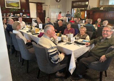 Smiling group of women and men at a Christmas lunch table.