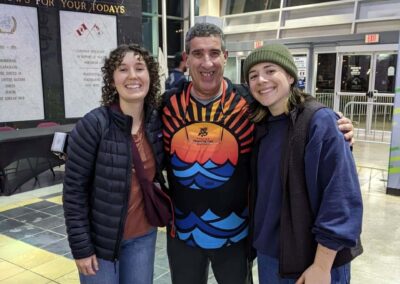 two women (student volunteers) standing with a man (VSRA member) at the Victoria Royals hockey game