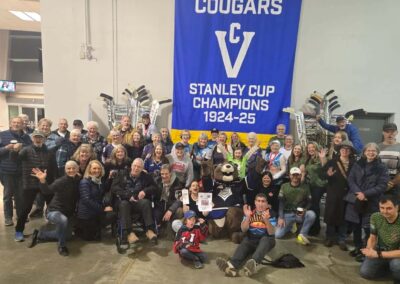 a group of about 50 people in front of the Cougars Stanley Cup Champions 1924-25 banner
