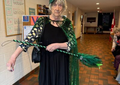 Woman with a green bow hat, green cape and green feathery broom