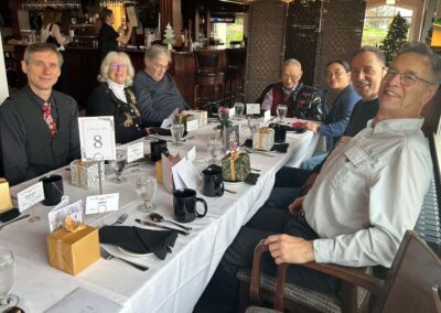 A group of happy guests sitting at a dining table, with little presents in front of each person. Waiting for the food.