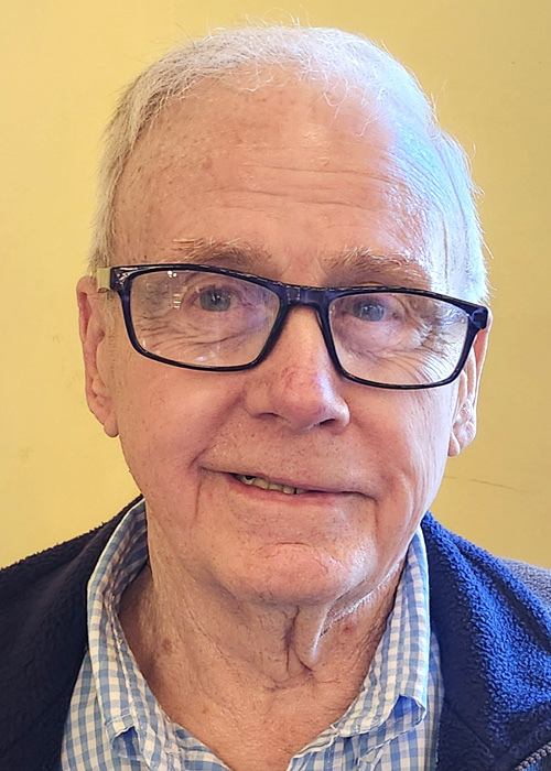 A smiling older man with lopsided glasses