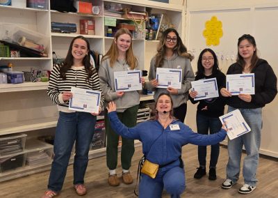 Five young adults and a woman stand holding certificates