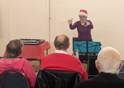 A smiling woman conducts a class of older people