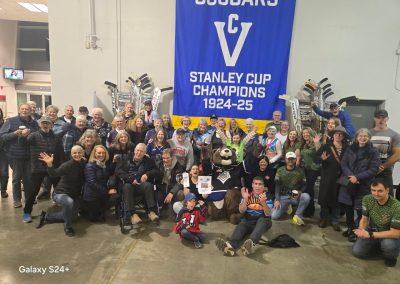 A group of people smiling around the Victoria Cougars banner