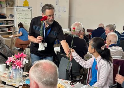 A man giving a woman a carnation at the VSRA Mother's Day tea