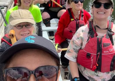 A group of adults wearing life jackets and holding paddles in a dragon boat.