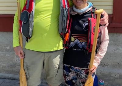 A man and woman standing together holding paddles.