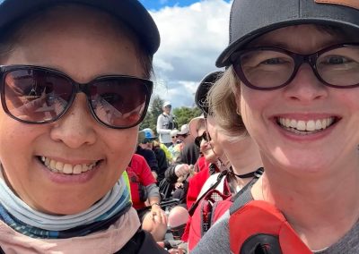 Two smiling women with baseball caps and glasses wearing lifejackets.