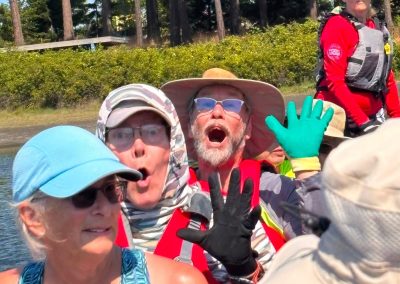 Women and men sitting in a dragon boat pretending to be scared.