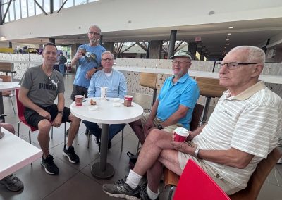 Five men sitting around a round table with coffee cups, smiling