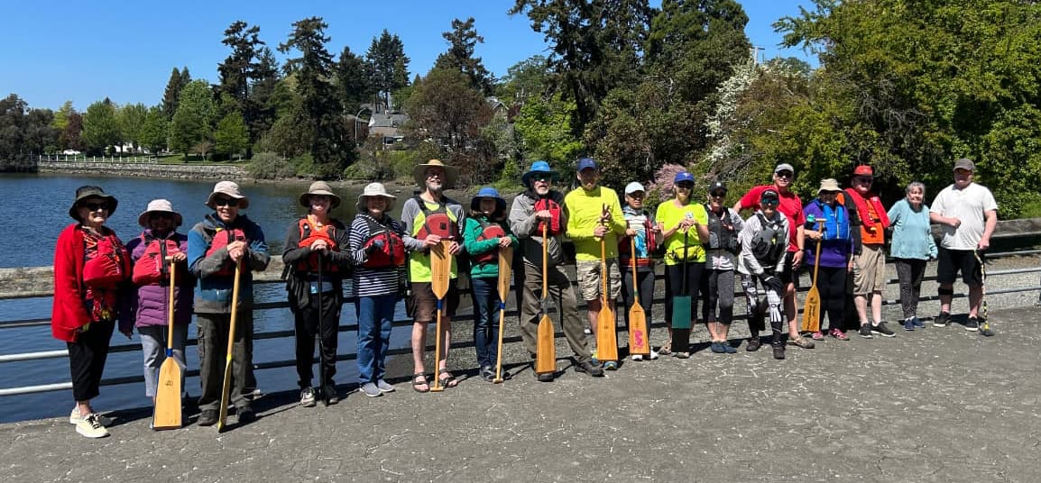 Group of people in standing with paddles beside the water