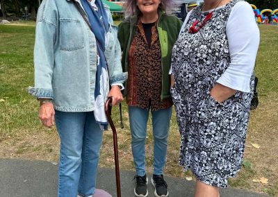 Three older women standing in Gyro Park with beaming smiles.
